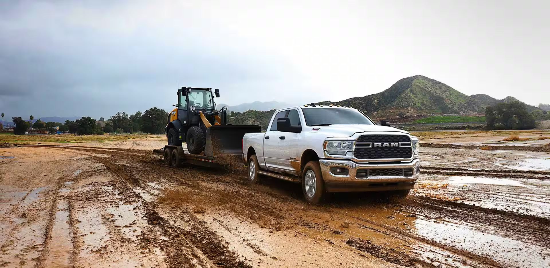 a white truck hauling heavy equipment in the mud