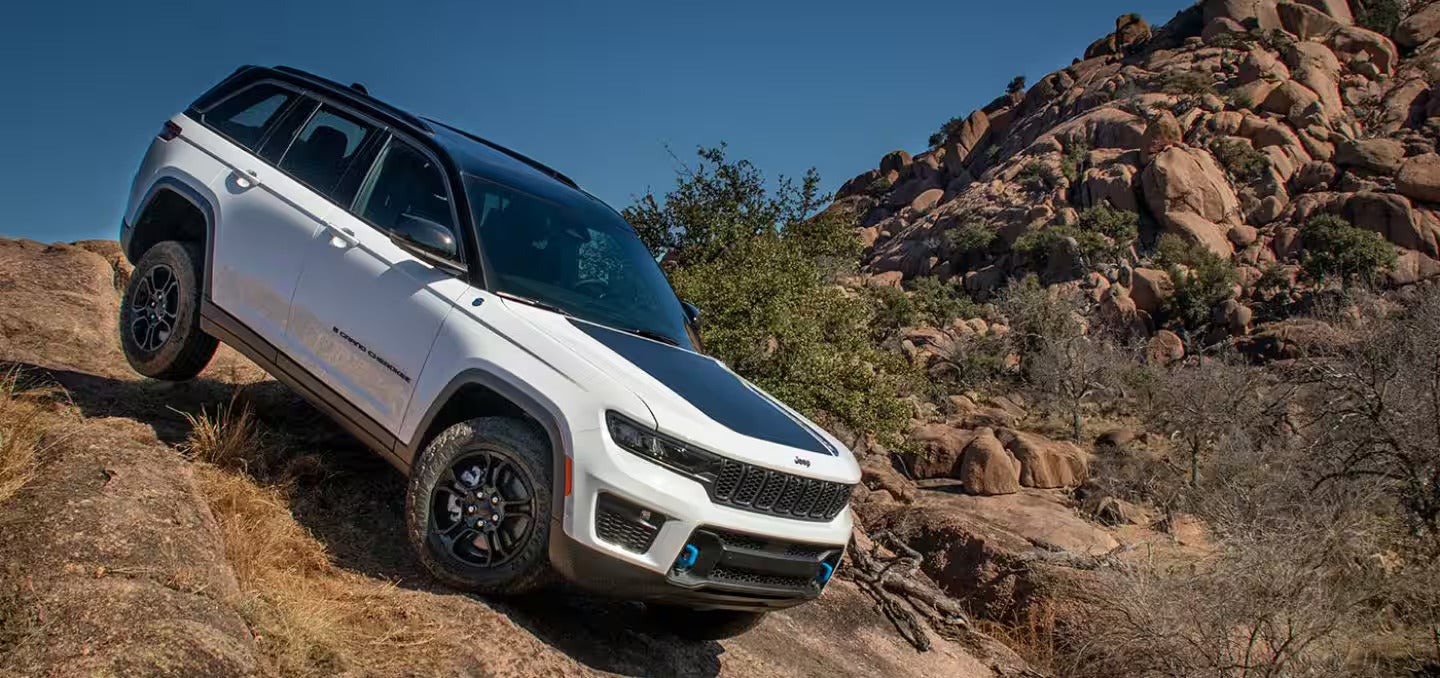 a white jeep suv driving down boulders